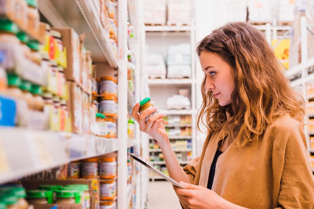 Una mujer mira la composición de un producto en busca de aditivos que Destruyen el corazón y el cerebro