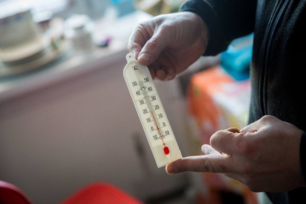 Un hombre sostiene un termómetro en sus manos