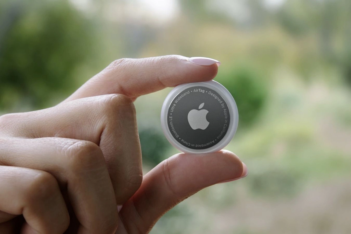 Una mujer sostiene un AirTag con dos dedos